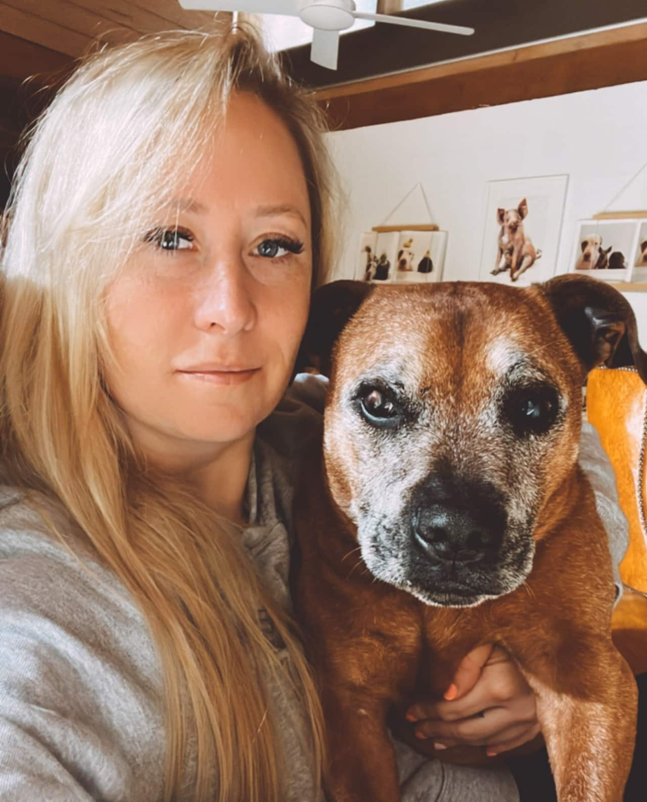 A blonde woman holding a brown dog.