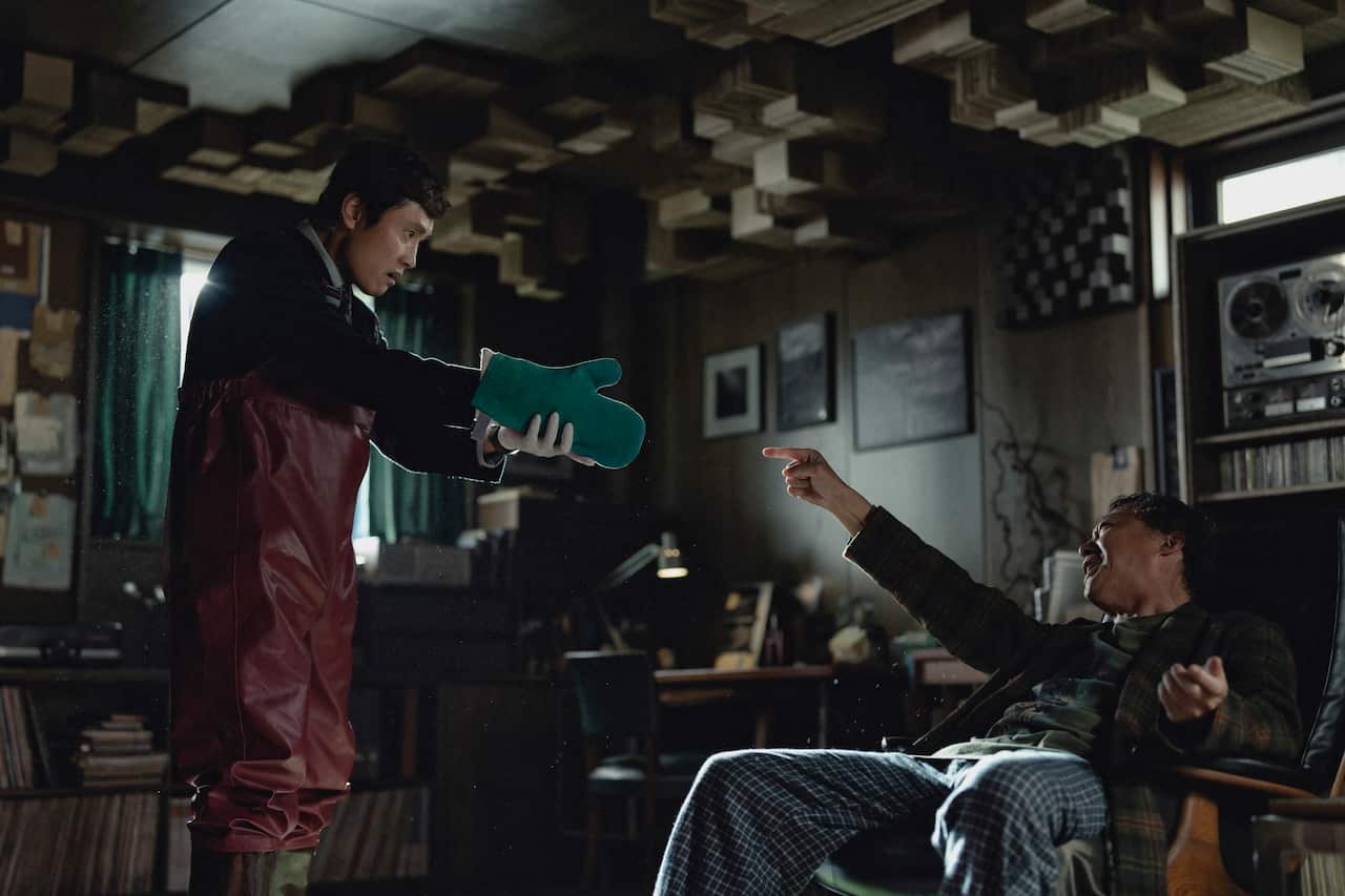 Um homem segurando uma luva de forno na frente do rosto de outro homem.