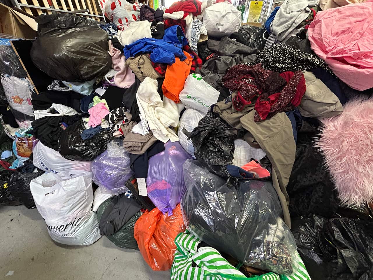 A pile of bin bags, cardboard boxes and other bags with clothing