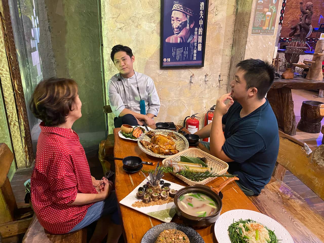 三个人坐在一张桌子旁,桌子上的盘子和篮子里放着各种各样的食物。