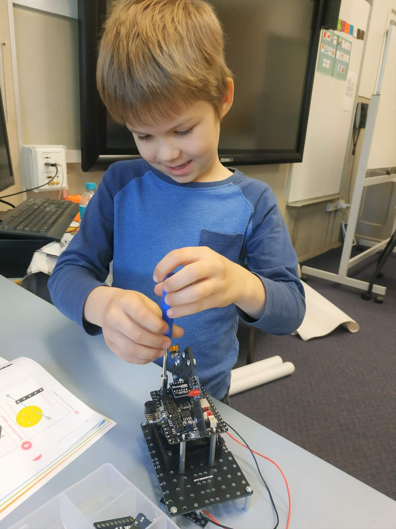 A boy standing at a table and working on a robot