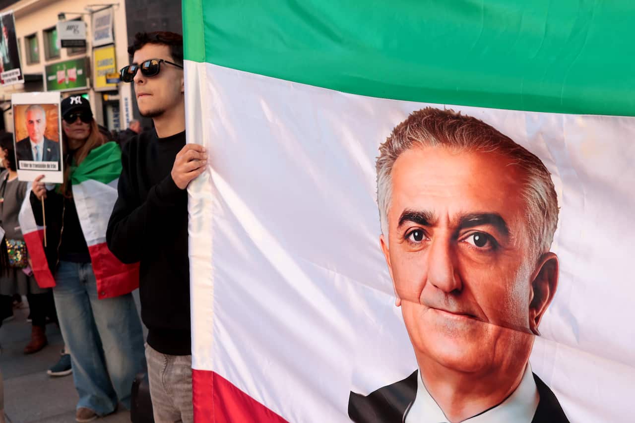 Demonstrators hold an Iranian flag with a man's face on it.