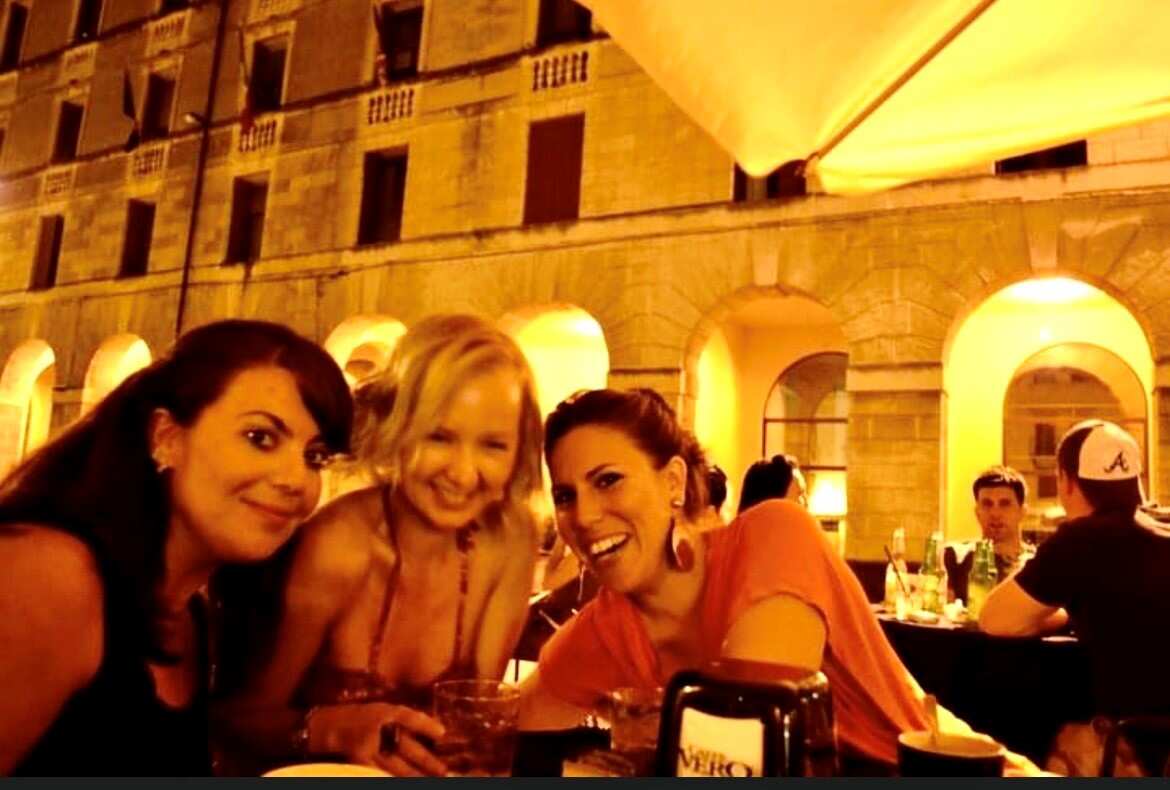 Kimberley Mitchell with two other women laughing at an outdoor cafe.