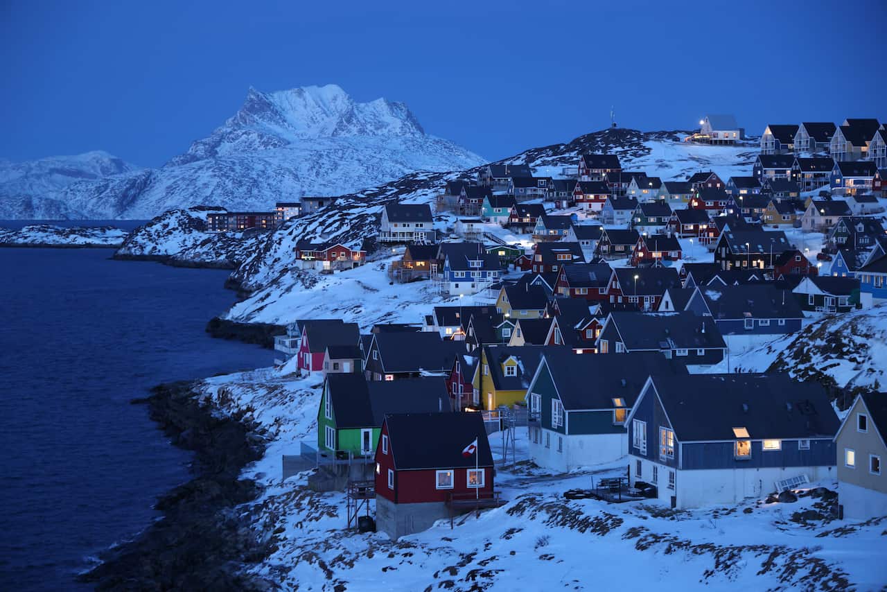 Residential houses stand at a fjord at twilight.
