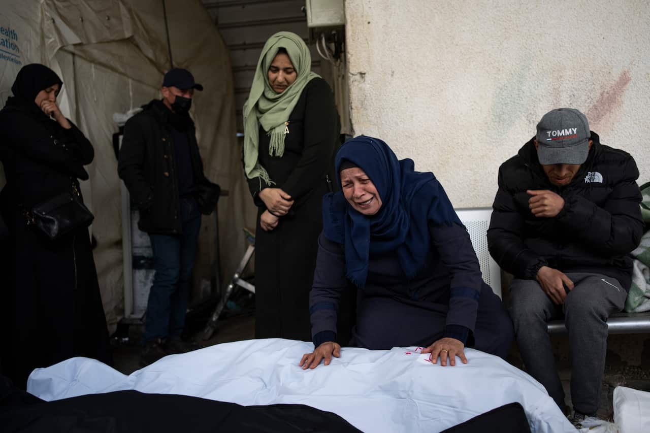 A woman mourns a dead relative wrapped in white shroud