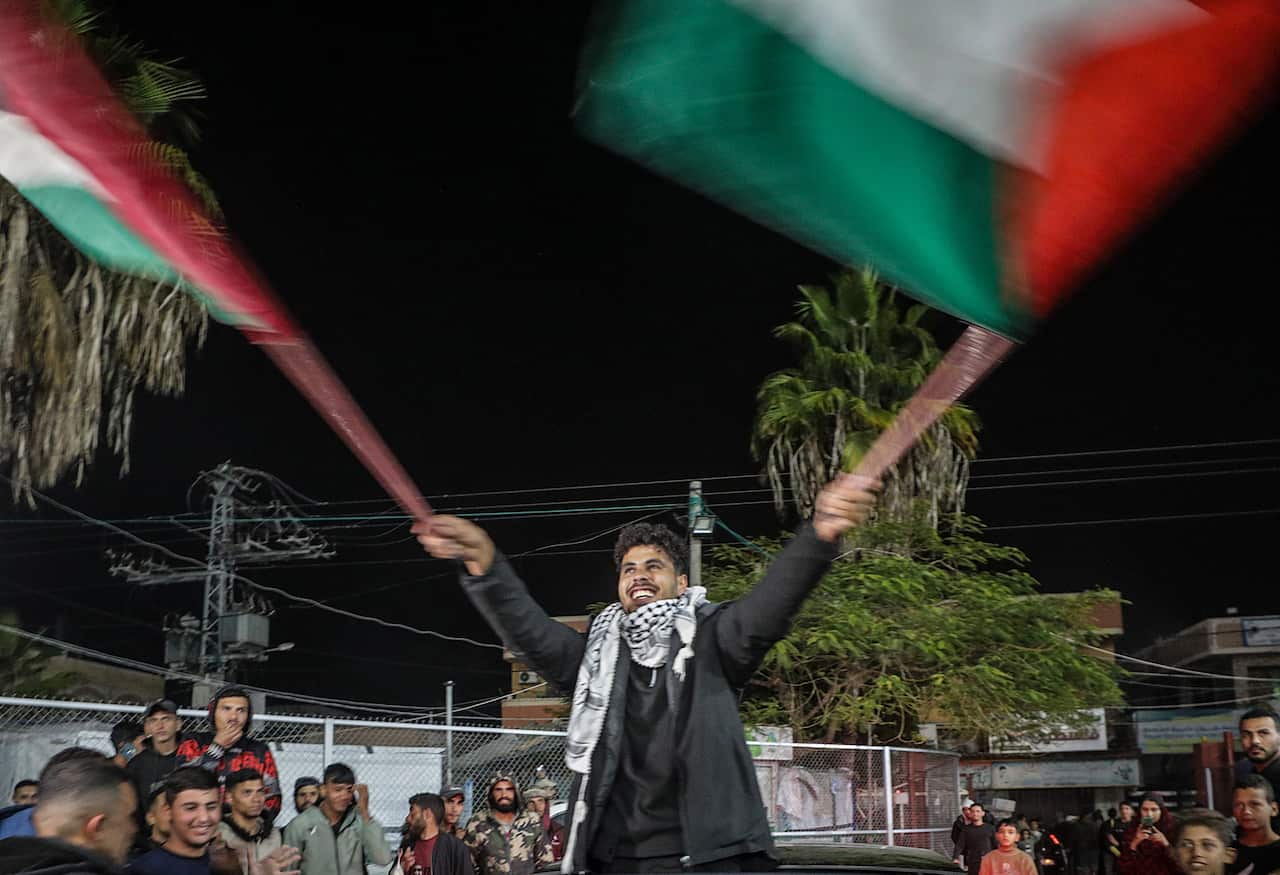 A man smiling waves a Palestinian flag