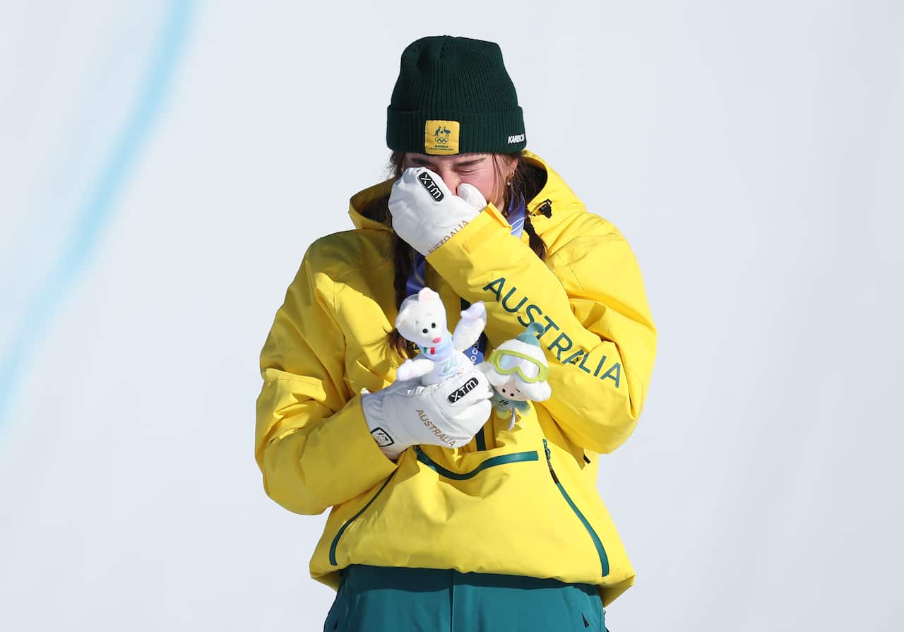 A woman in an Australian jersey cries at the snow.