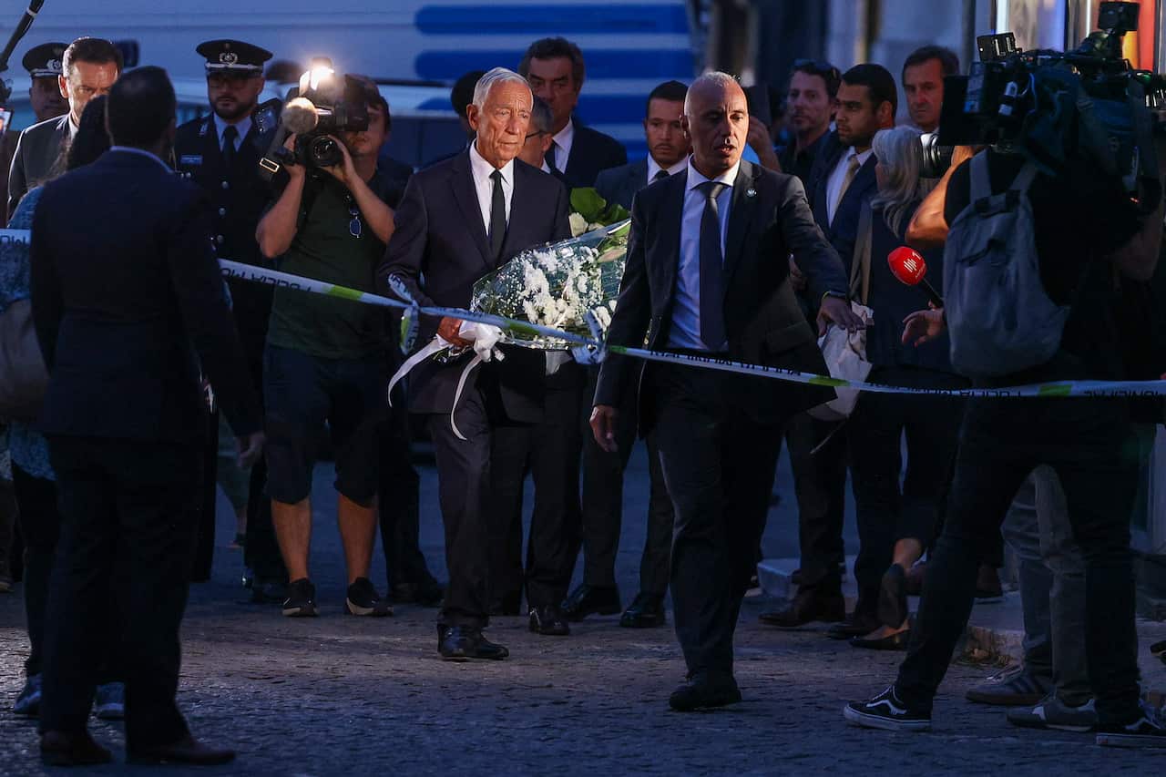 A man carries flowers, paying respect to victims of a funicular crash in London.