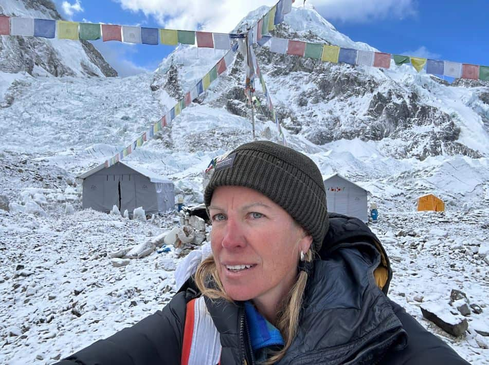 A woman wearing a beanie infront of snow covered tents.