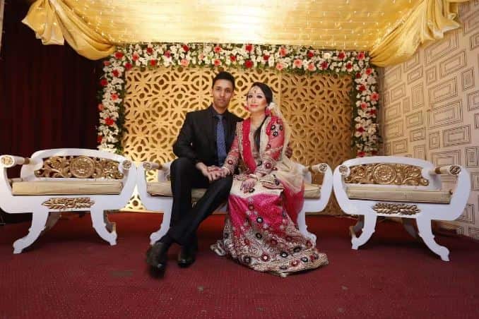 A man and woman sit on chairs, posing together. 