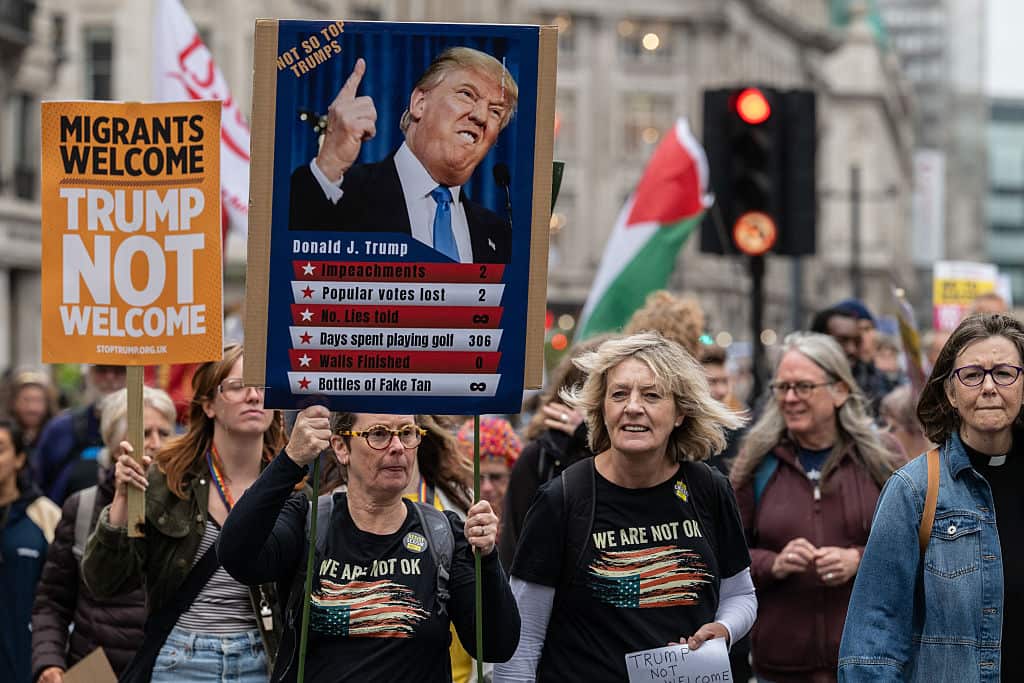 Protesters holding placards denouncing Donald Trump's visit march through central London. 