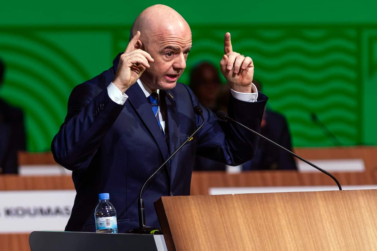 FIFA President Gianni Infantino at a lectern, using his arms to emphasise a point.