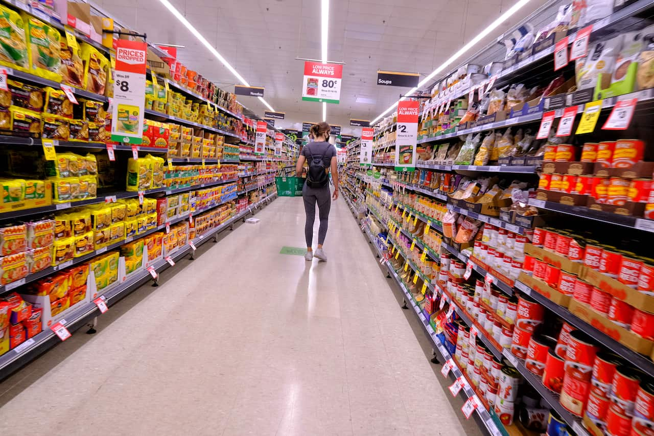 A person walking down an aisle at a supermarket.