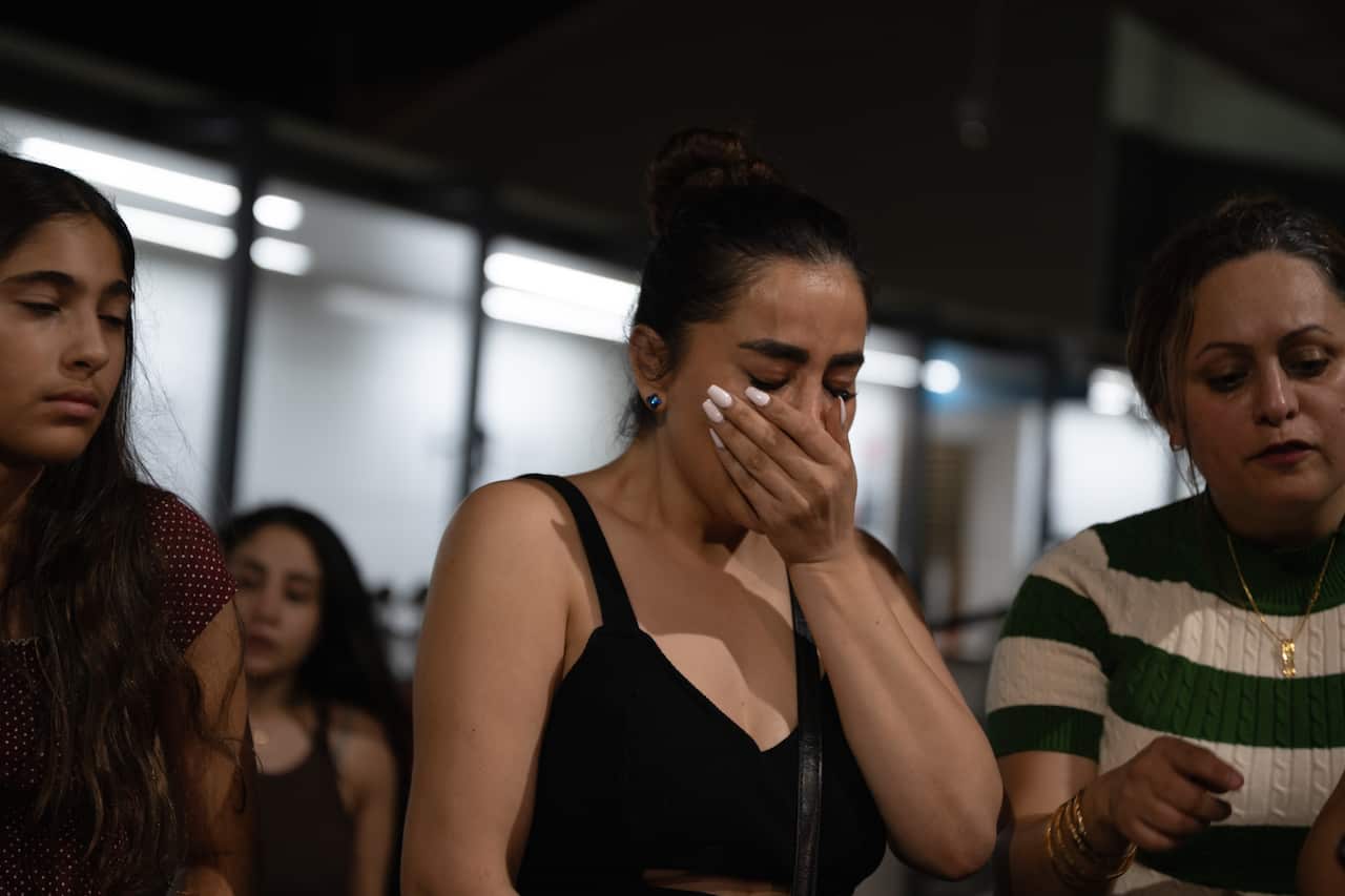 A woman with her hand in her face, crying. She is surrounded by three other women.