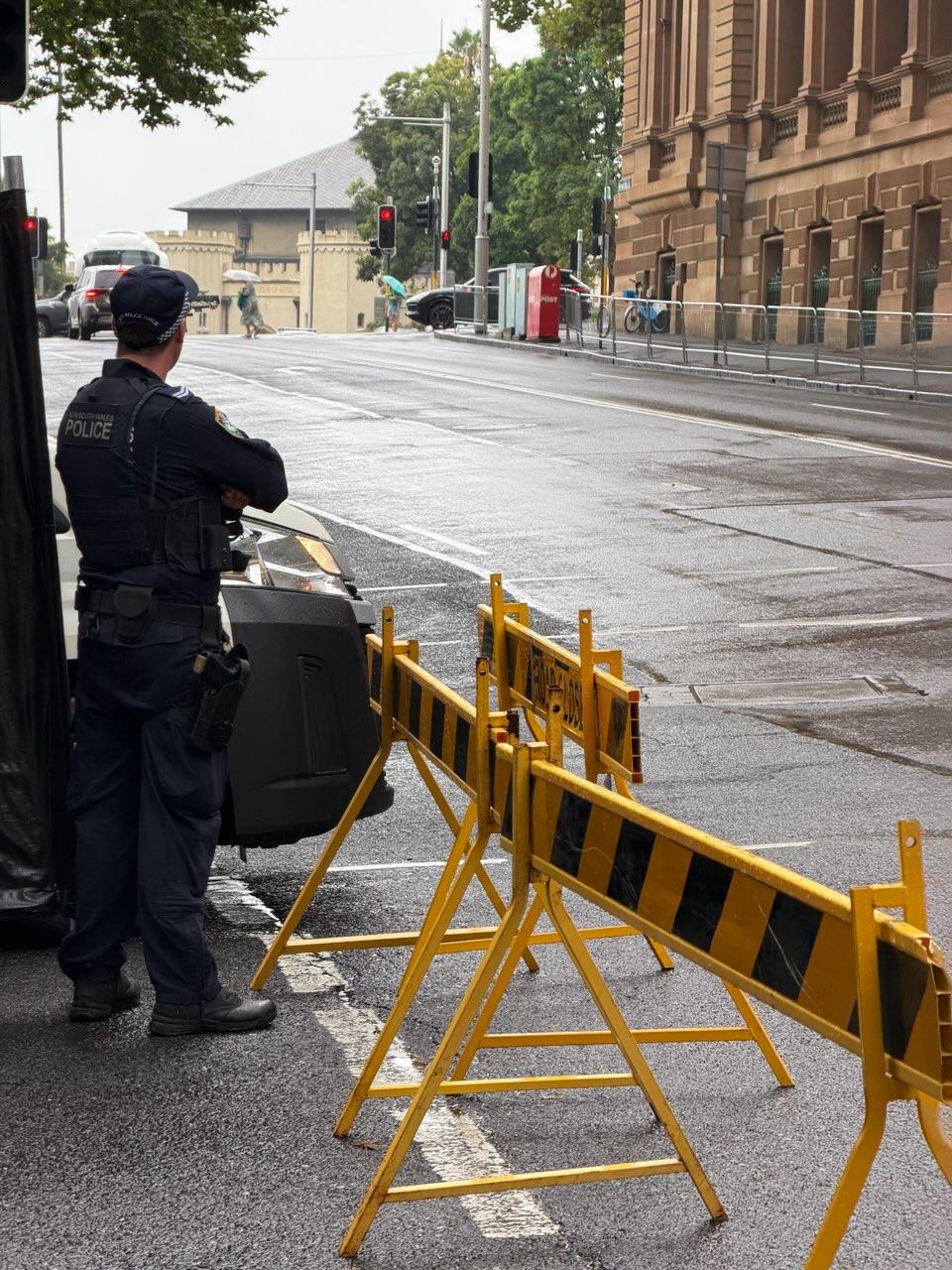 A police officer standing before a barricade next to a city street. 