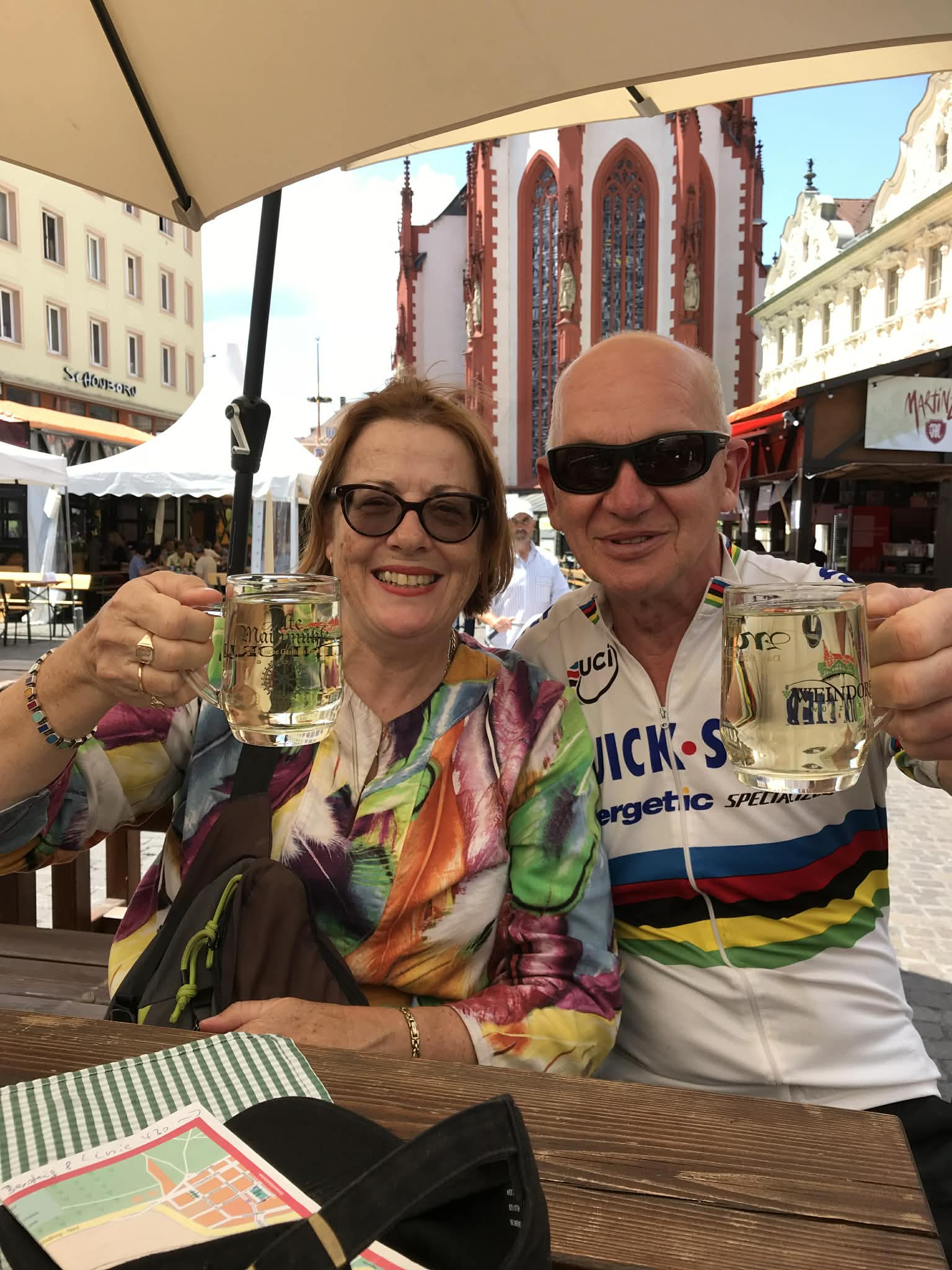 A couple smiling with beers in a European city.