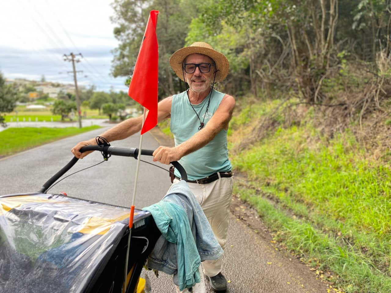 A man walking along a road pushing a buggy.