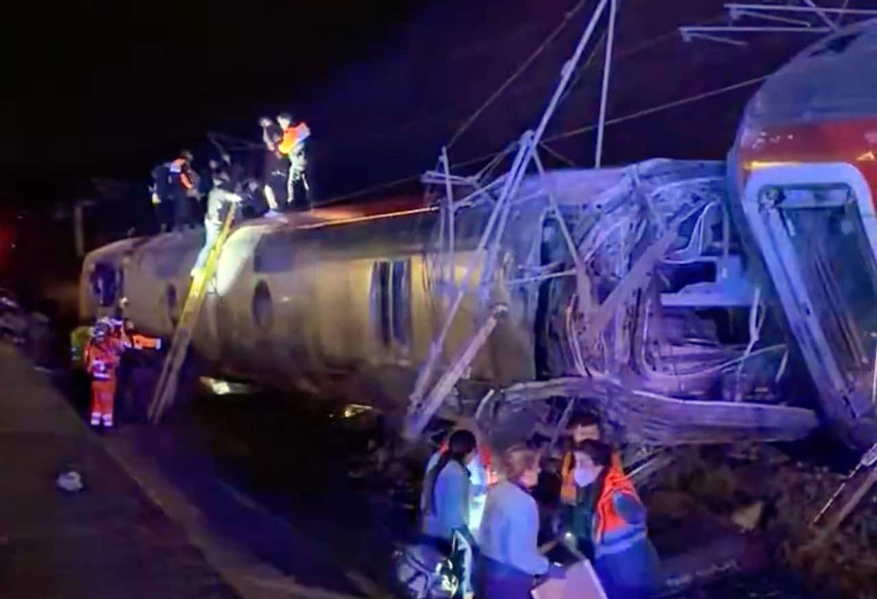 Emergency personnel working around a wreckage of a train.