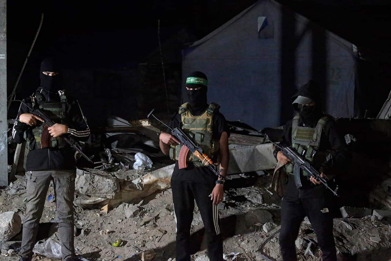 Men wearing black balaclavas and holding large guns.