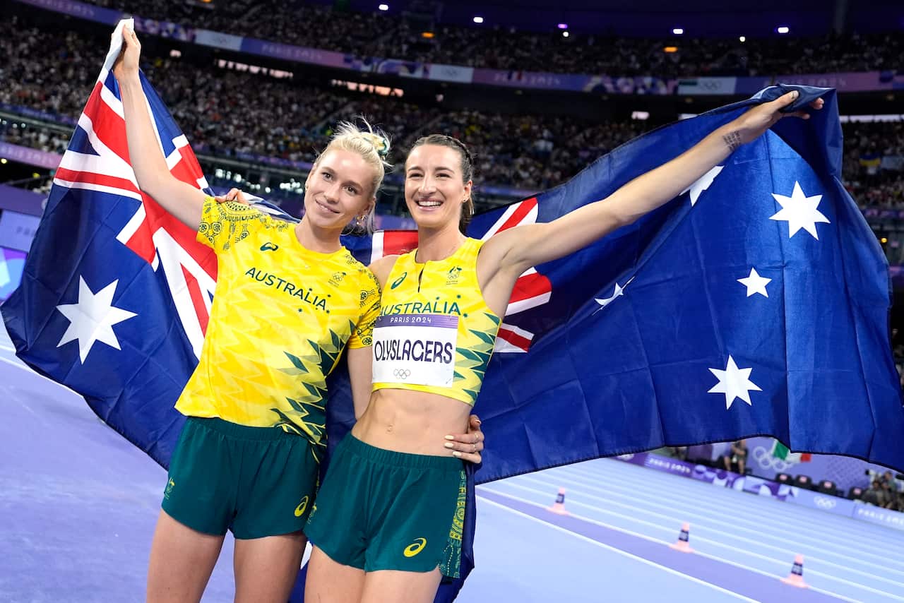 Two smiling women holding an Australian flag