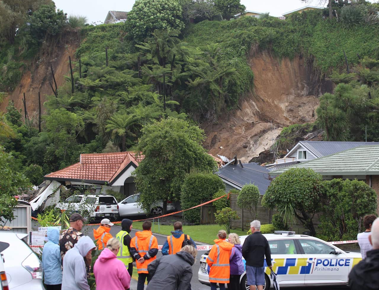 A group of people stand at the base of a hillside that has collapse