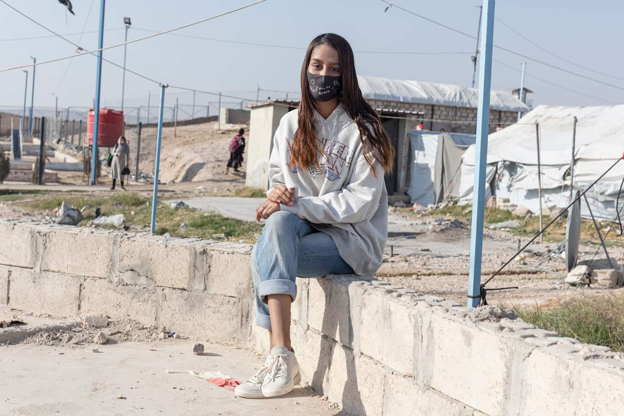 A woman sitting on a ledge posing for a photo.
