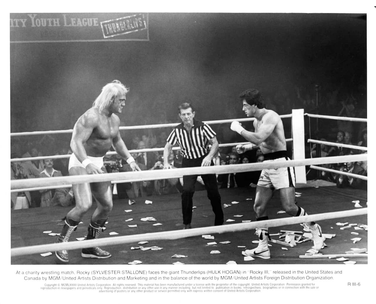 Black and white image of two boxers and a referee in a boxing ring.