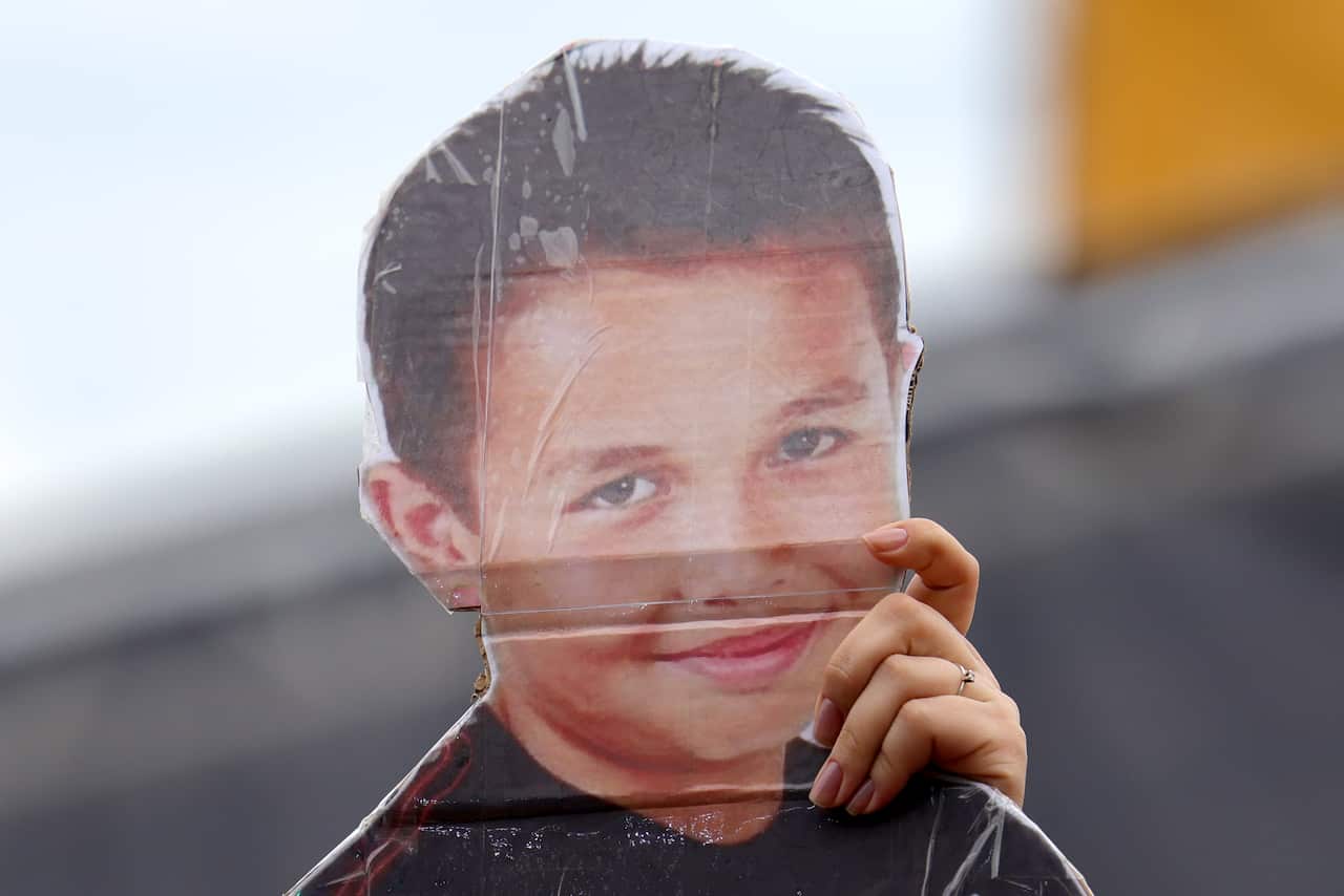 A fan holding a cut-out of a race driver when they were younger.