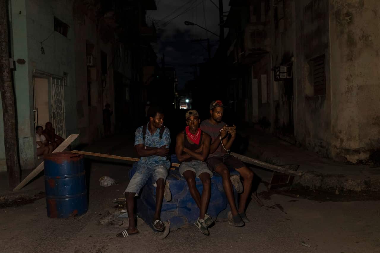 Los residentes se paran junto a una barricada que levantaron para bloquear una carretera durante una protesta que pedía el restablecimiento de los servicios eléctricos después de cuatro días de cortes de energía causados por el huracán Ian, en La Habana, Cuba, el viernes 30 de septiembre de 2022.