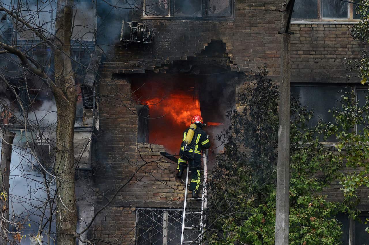 A firefighter climbs a ladder to enter a fire in a Kyiv apartment block