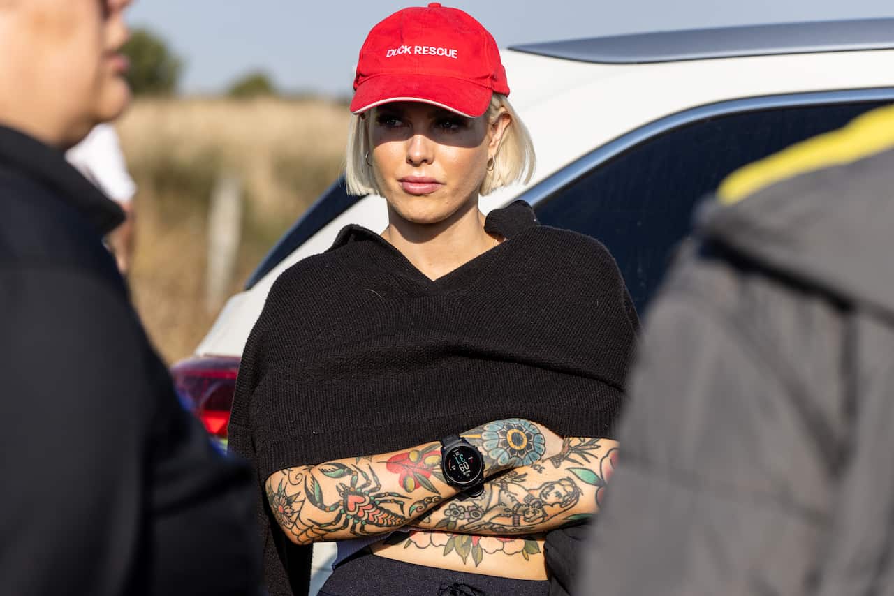 A woman wearing a red hat that says 'Duck Rescue' with crossed arms.