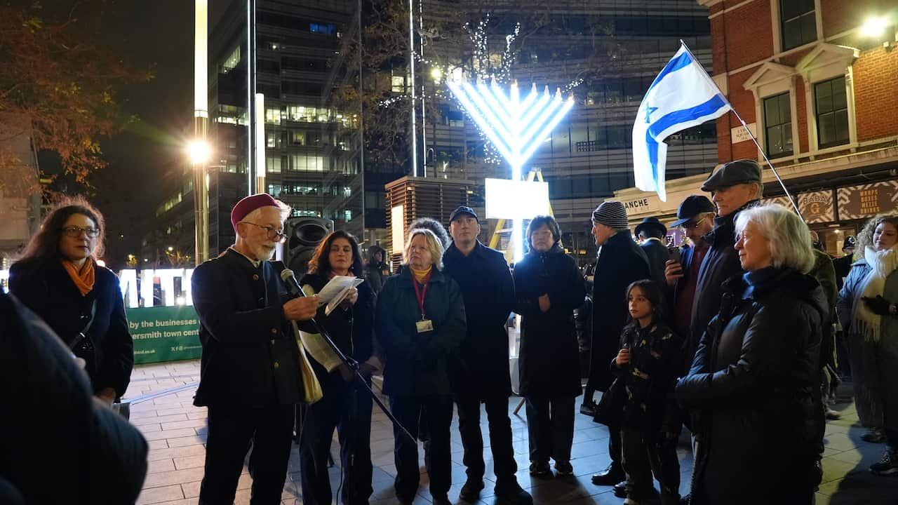 A man holding a microphone is standing next to a group of people.