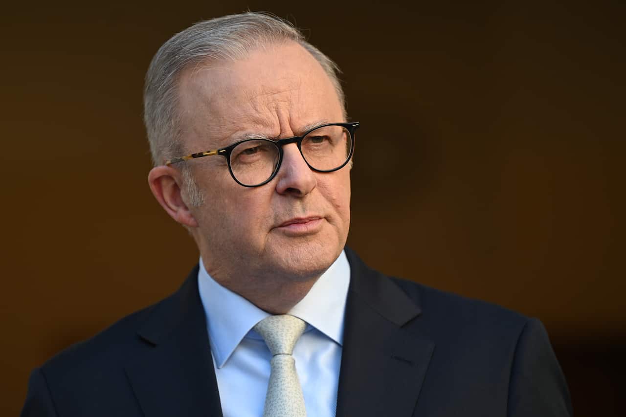 Anthony Albanese is wearing glasses and a black suit.