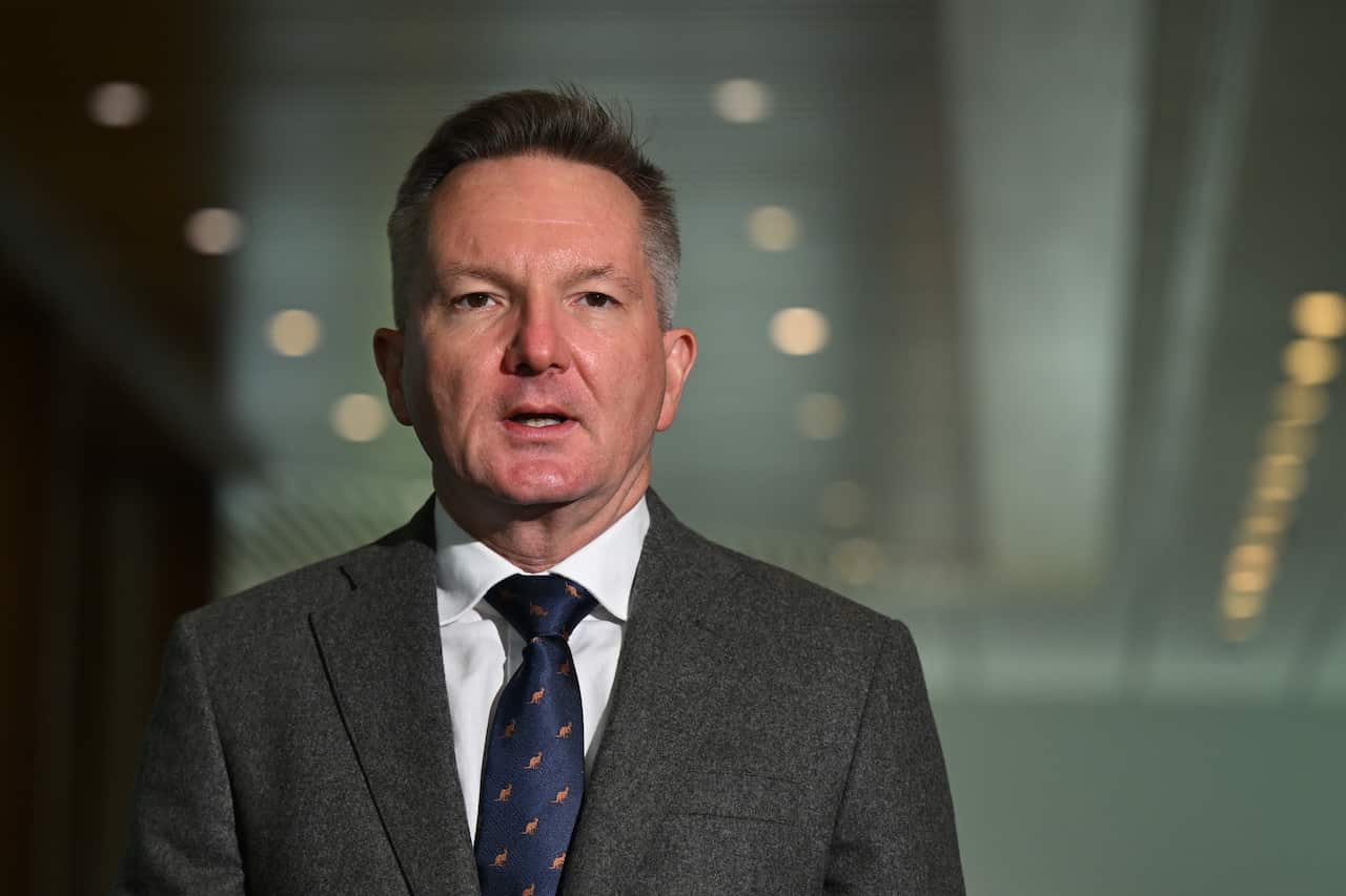 Chris Bowen wearing a grey suit standing in a hallway.