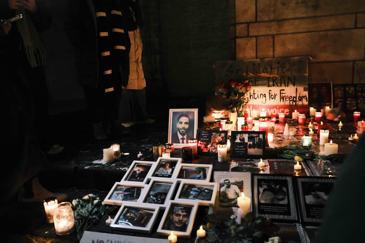 Photos of people in frames amid candles