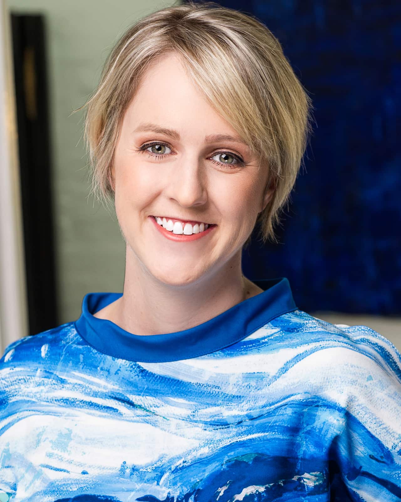 Headshot of woman with short blonde hair wearing a blue and white top.