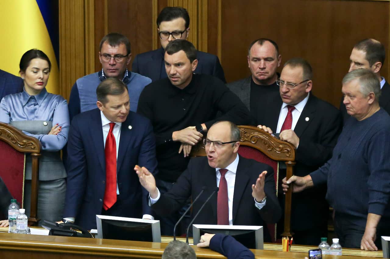 People crowd around a speaker in parliament.