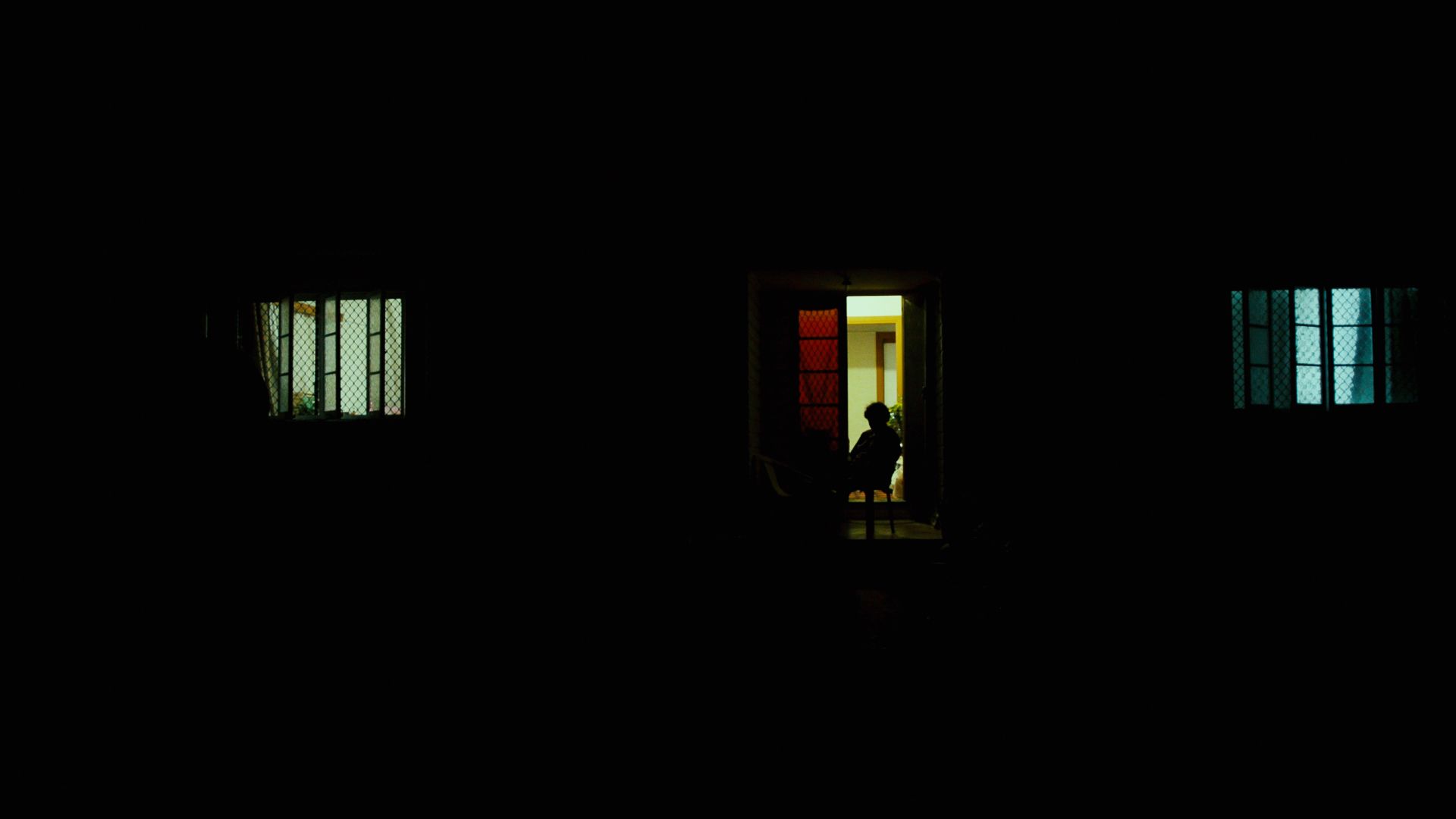 Image of person sitting in the doorway of a house at night, sillouhetted