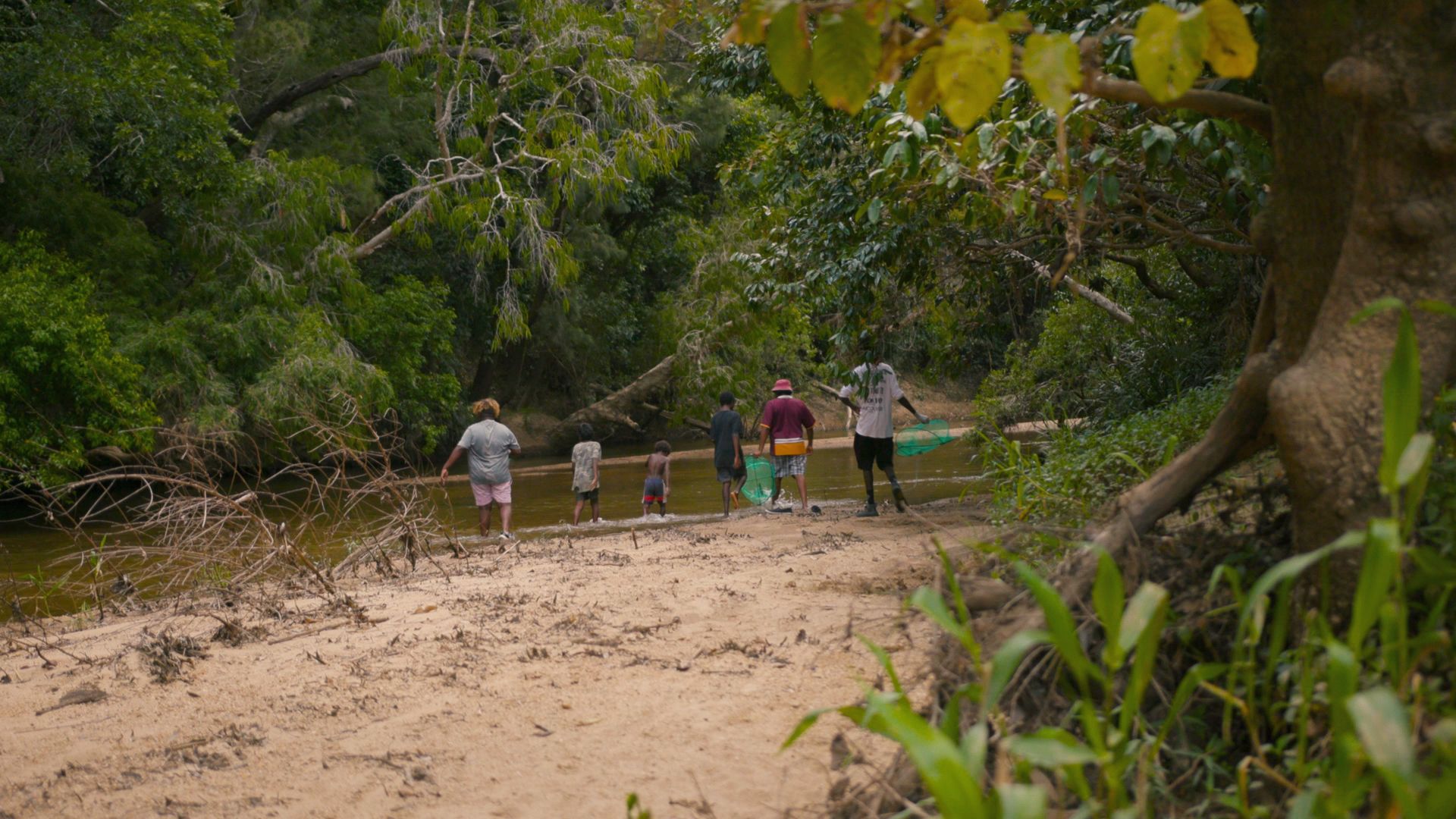 Image of a group of young people, fishing with adults by a creek in North Queensland