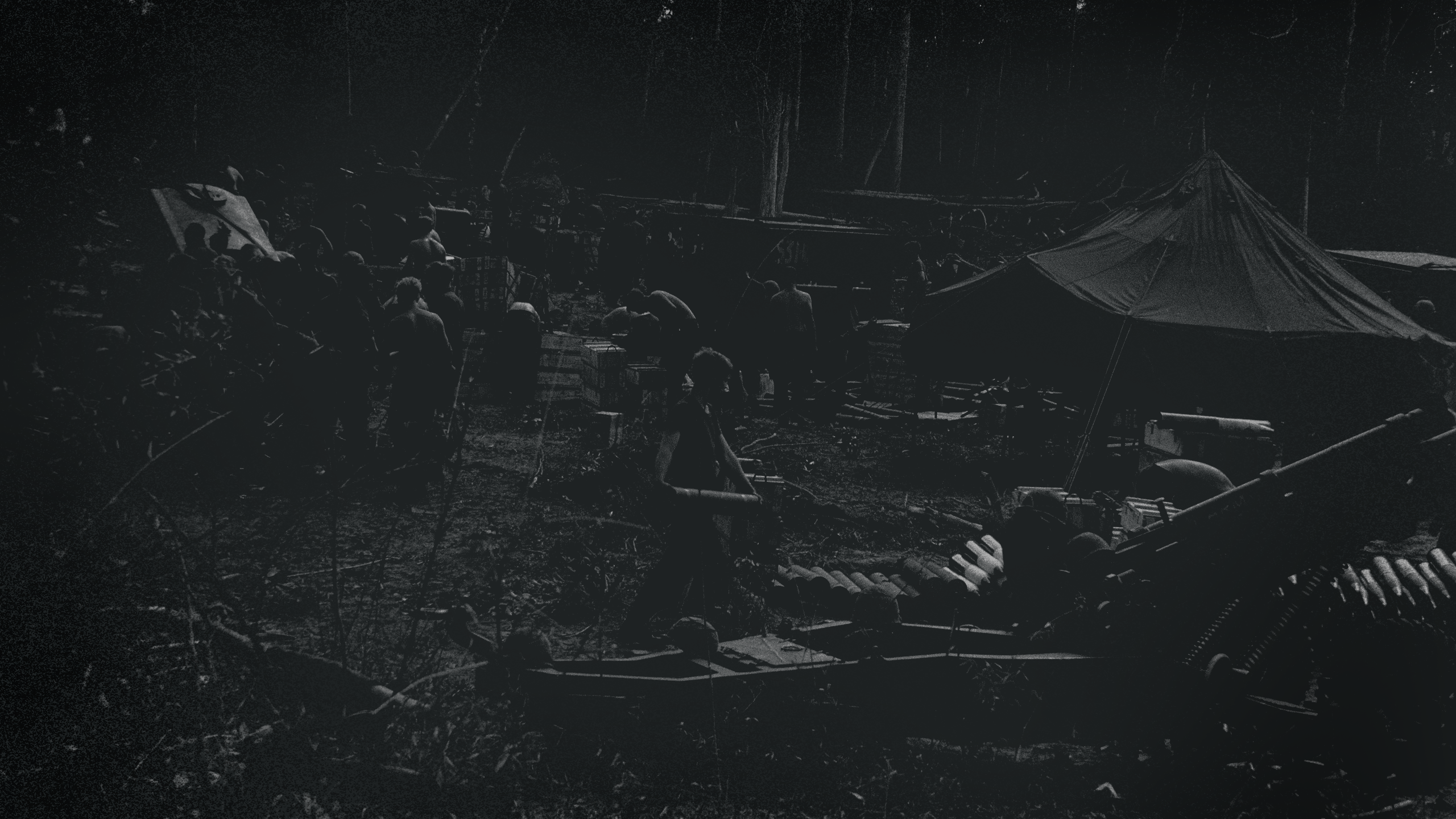 Darkened image of army camp in Vietnam with tents and weapons