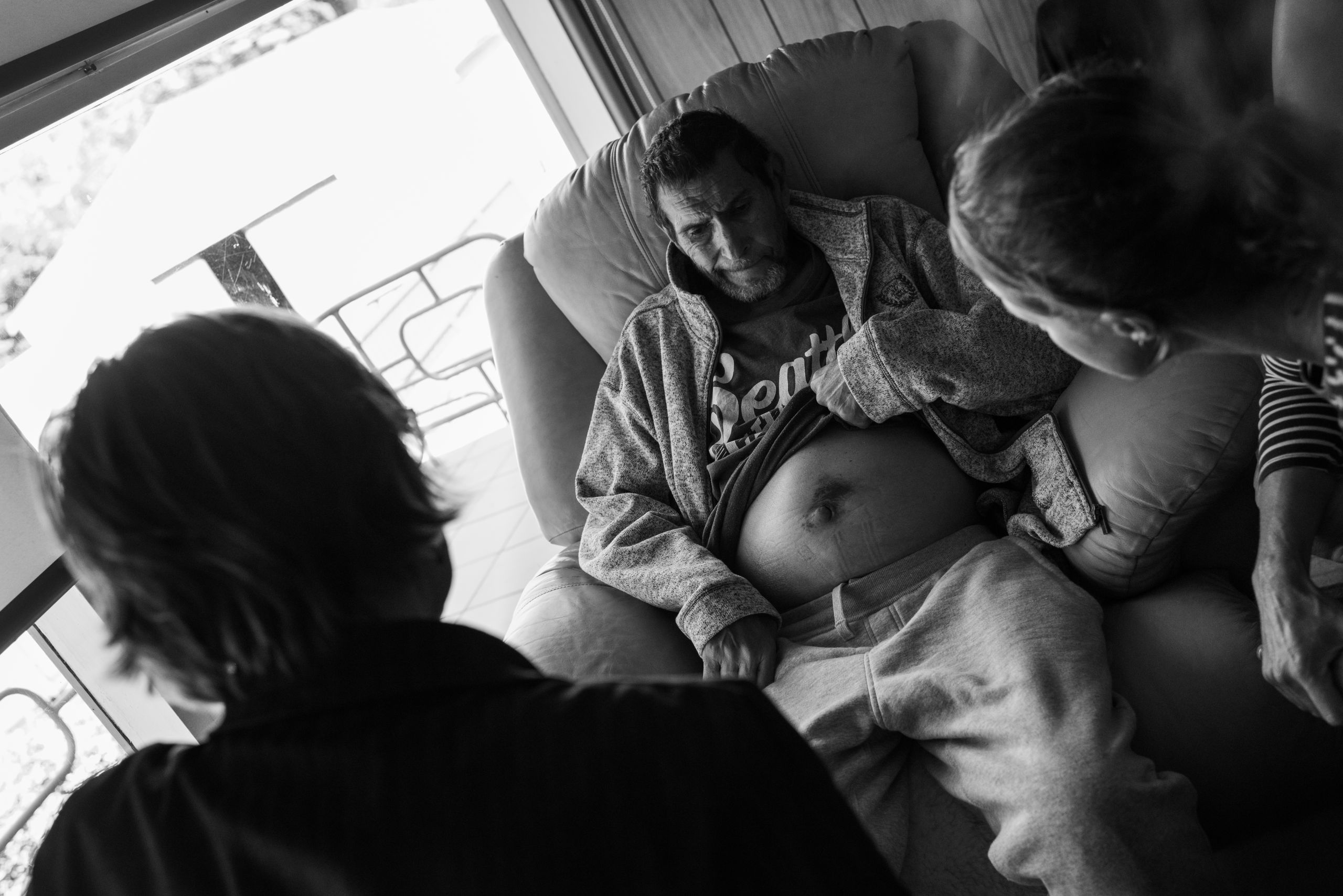 Deana Efraemson (RN, NSW Health Eurobodalla Community Nurse) and senior Nurse Practitioner, Theresa Pot (left), consult on the swelling of Glen's belly and what is causing it, which they determine to be mainly from the liver cancer. 10 April 2019. Yuin Country (Central Tilba, NSW).
