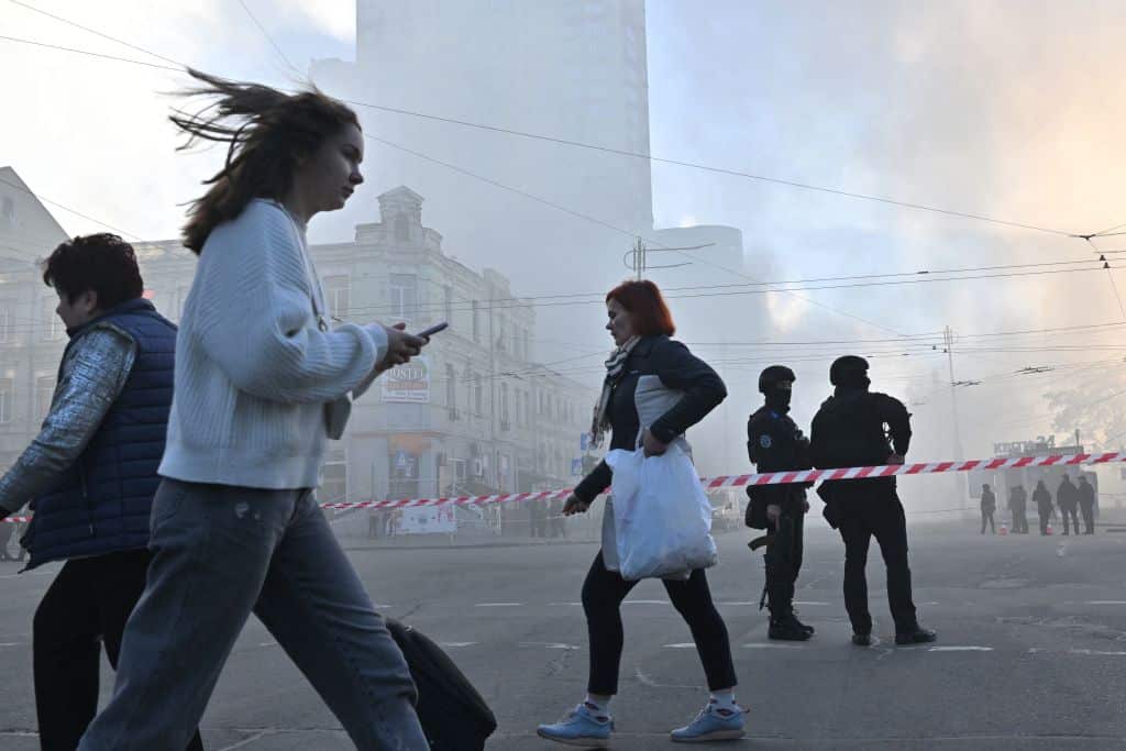 Local residents walk past police officers after a drone attack in Kyiv.