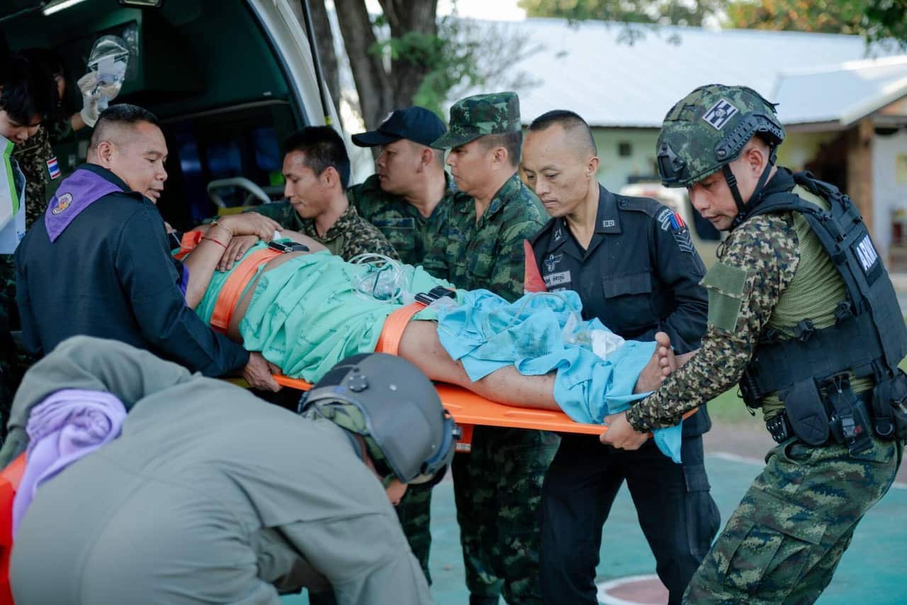 A man on a stretcher is loaded into a vehicle by men wearing uniforms