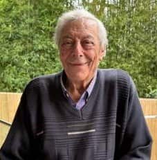 An older man with short grey hair smiling for the camera