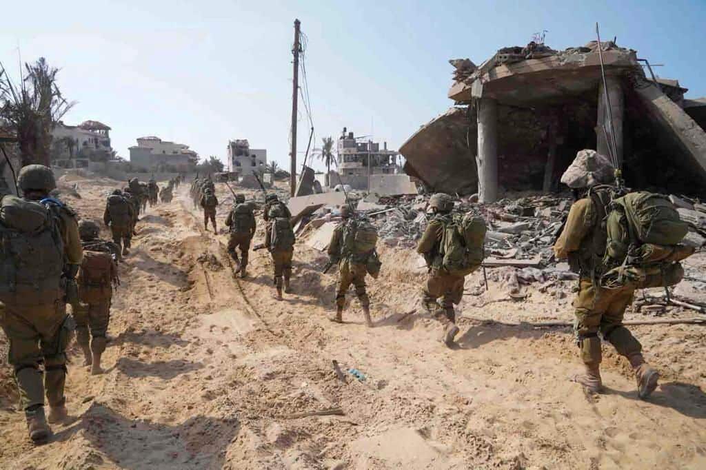 A group of soldiers walk through rubble.