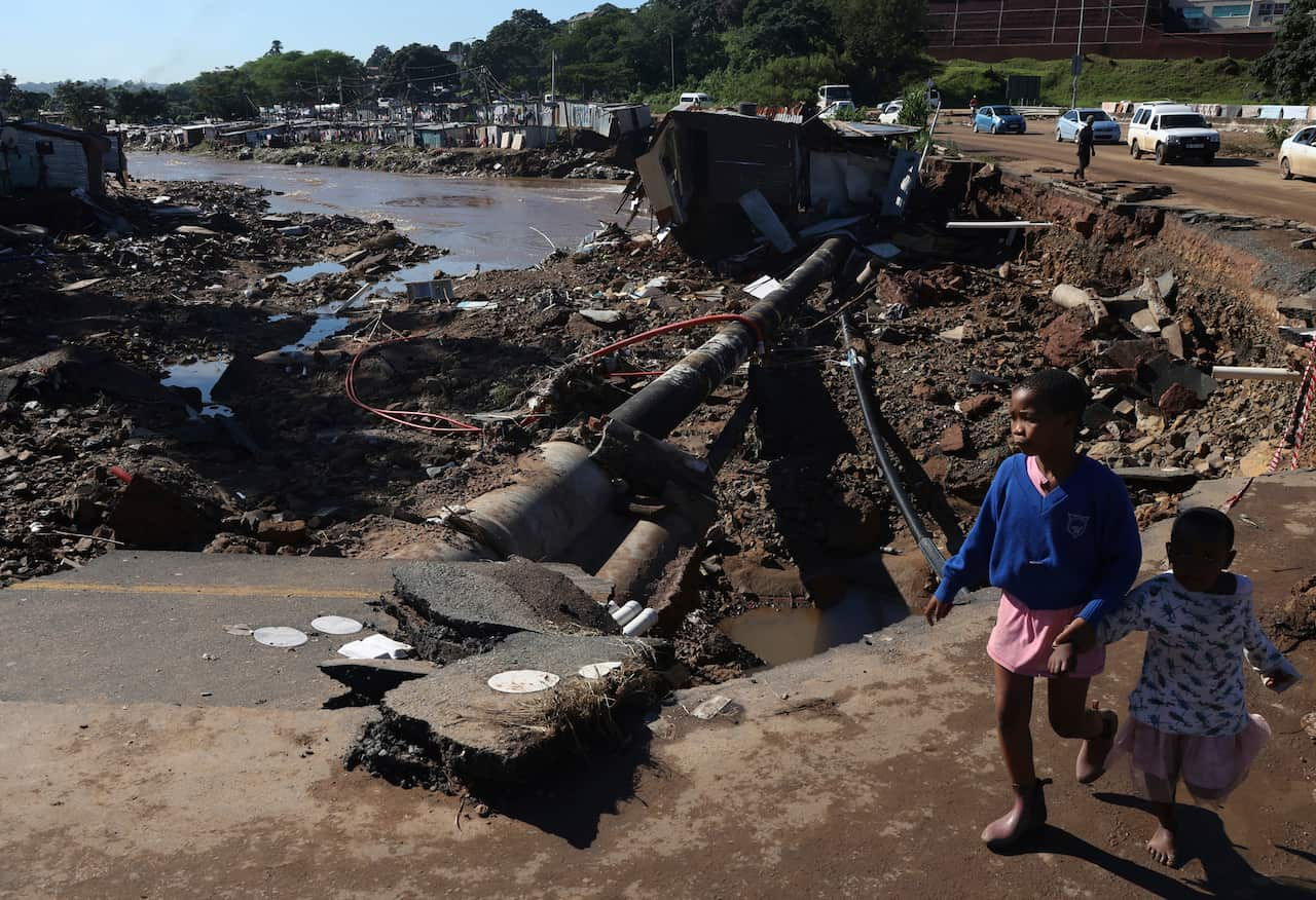 Children walking along a damaged road.