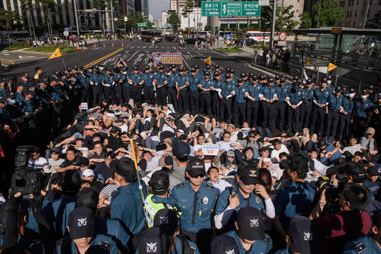 Anti-gay religious activists lie in a street surrounded by police as they attempt to block the Seoul Queer Parade from passing along a street in Seoul on July 14, 2018.