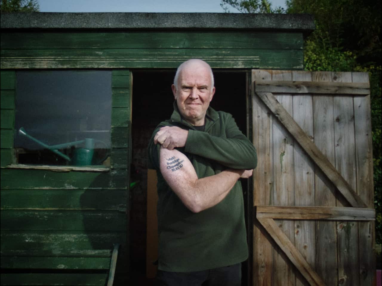 A man flexing his bicep with a tattoo on it.