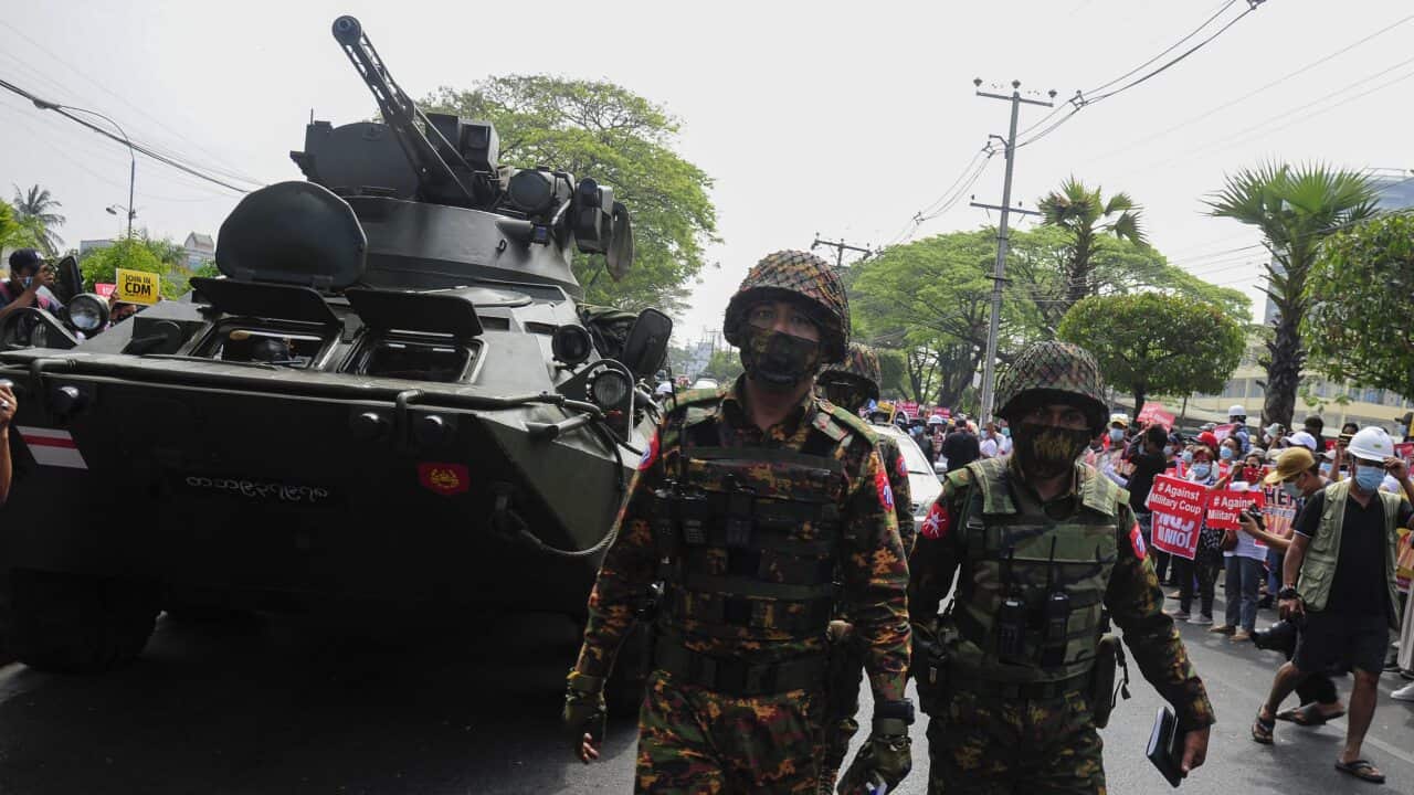 Soldiers walk near an armoured personnel carrier while people protest against the military coup, outside the Central Bank of Myanmar, in Yangon.
