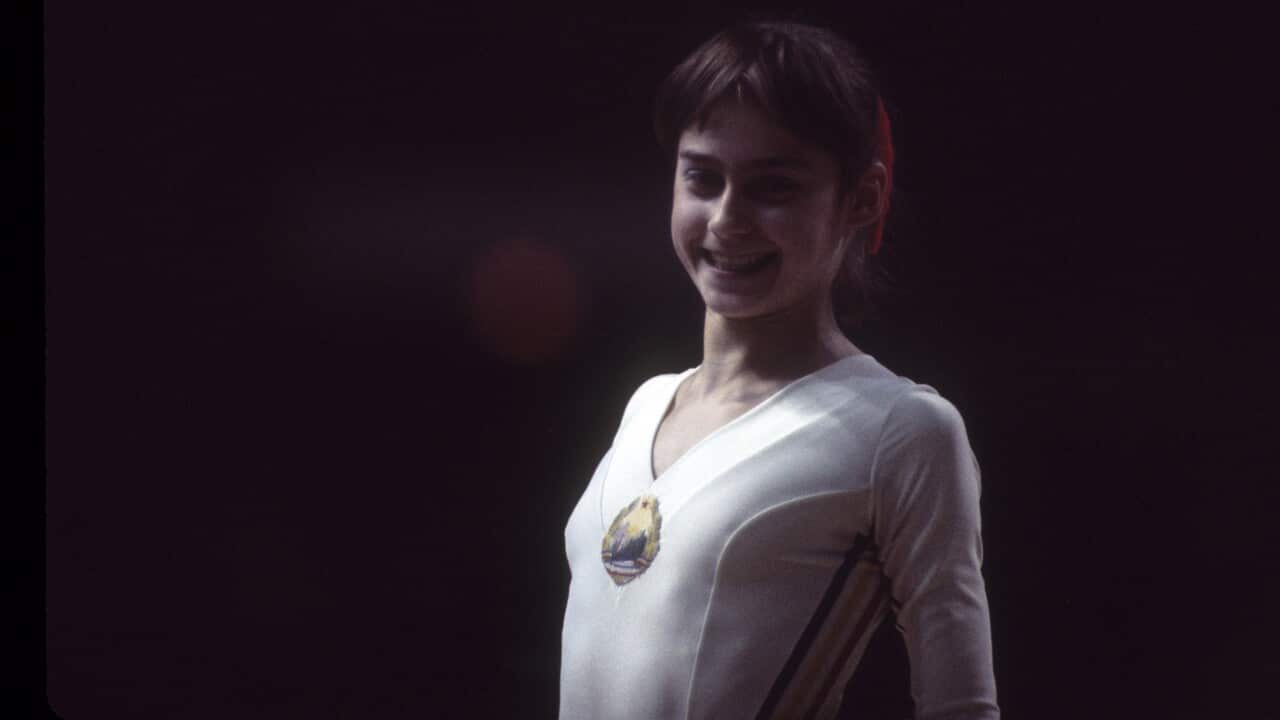 Nadia Comaneci at summer olympics 1976 smiling at camera in front of black background